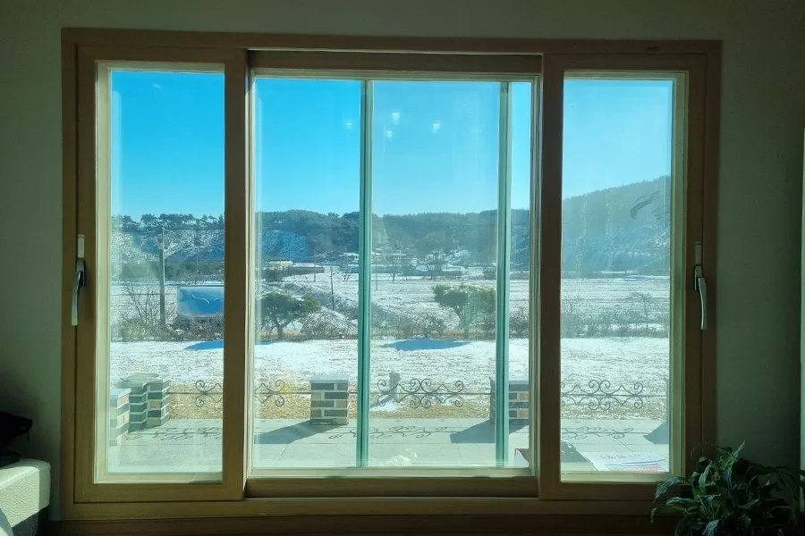 거실 통창 너머로 눈 덮인 산과 마을이 보이는 사진