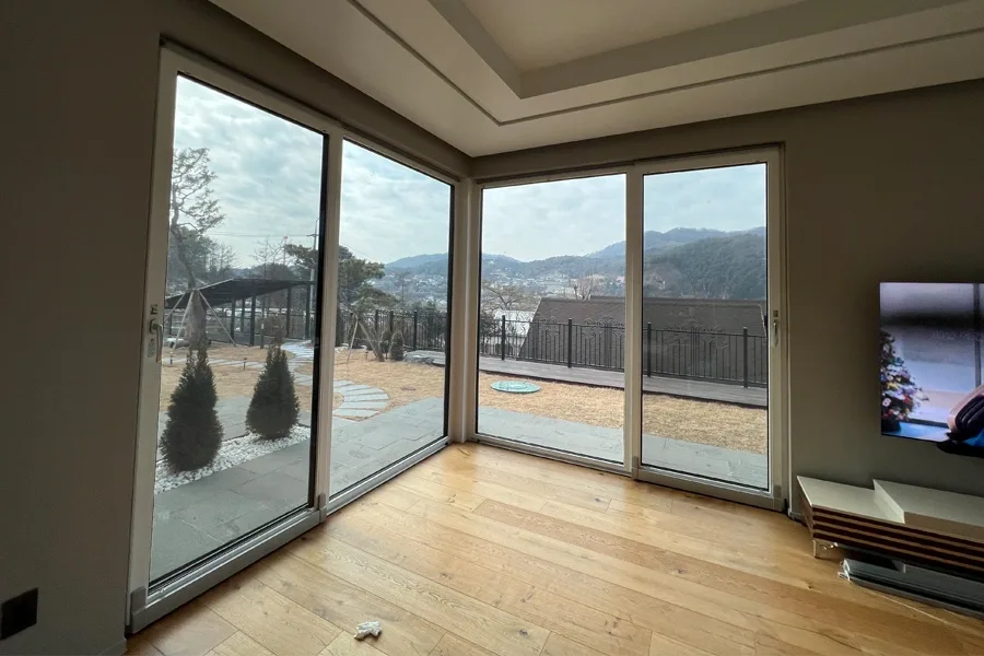 모서리에서 이어지는 통유리 사이로 마을 풍경이 보이는 사진