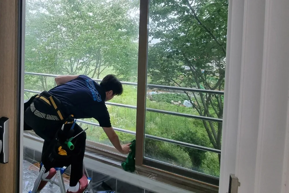 창밖 나무와 조경이 보이는 위치에서 필름을 마감 중인 사진