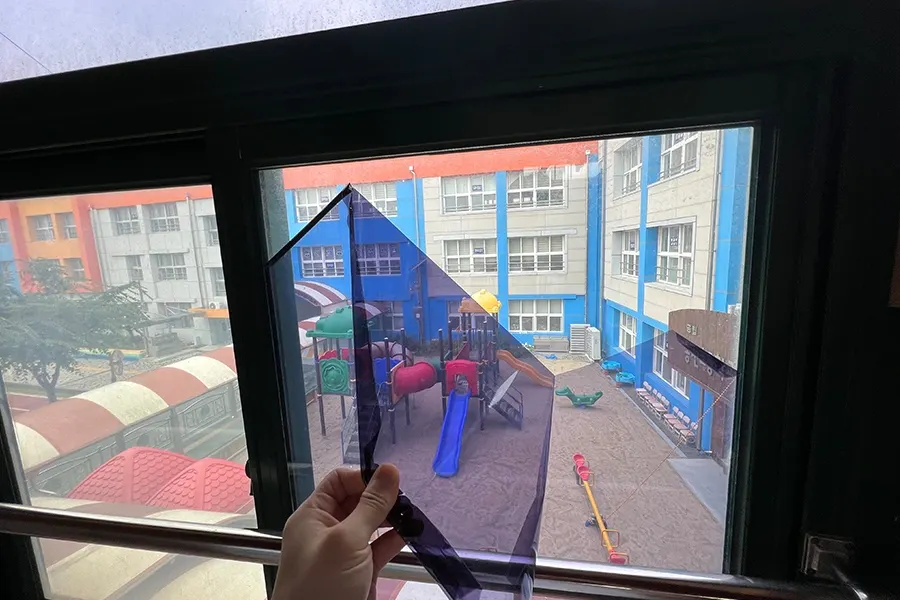 교실 창문에 필름 샘플을 대보며 톤을 확인하는 사진