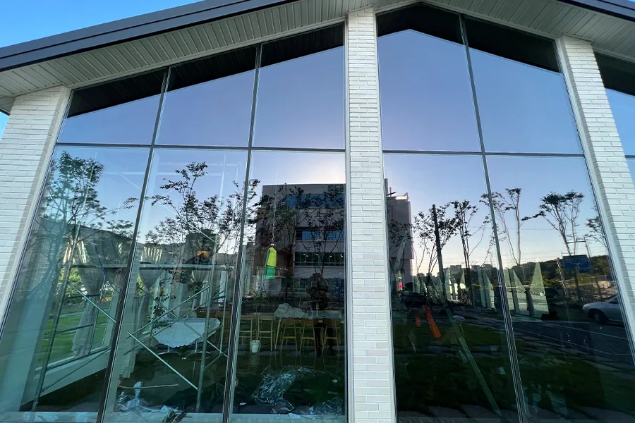노을을 배경으로 한 박공지붕 통유리 건물 외관 사진