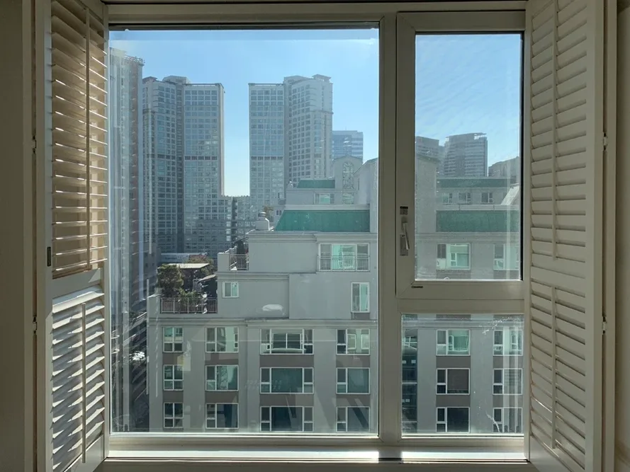 플랜테이션 셔터 창 너머로 보이는 고층 도심 전망 사진
