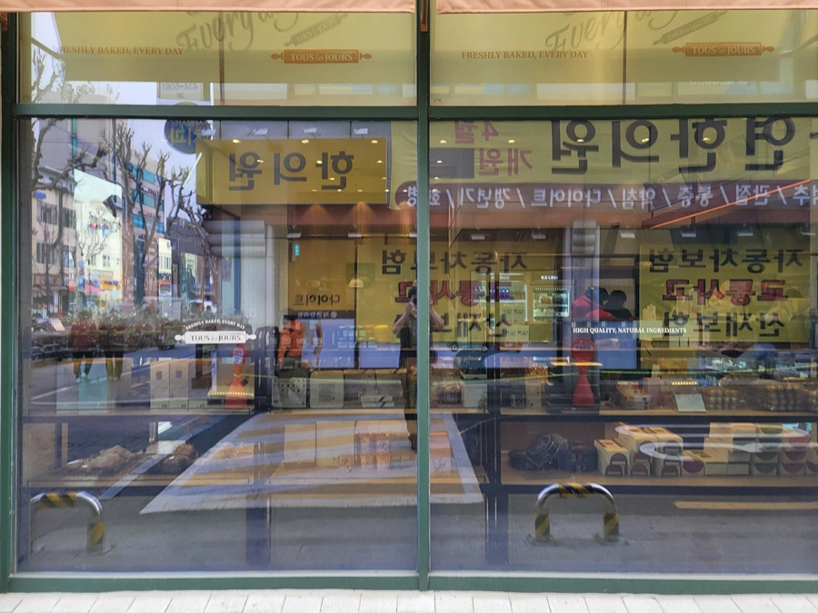 베이커리 매장 통유리에 붙은 로고와 진열창이 보이는 사진